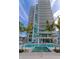 High-rise condo building with a pool, hot tub, palm trees, and lounge chairs under a bright blue sky at 301 Quay Cmn # 1005, Sarasota, FL 34236