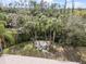 Aerial view of backyard fire pit with colorful Adirondack chairs, surrounded by lush greenery and mature palm trees at 3189 Seattle Ave, North Port, FL 34286