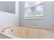 Close up on soaking tub with marble surround in bright bathroom with window at 3189 Seattle Ave, North Port, FL 34286