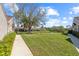 A well-maintained backyard featuring lush green grass, mature trees, and a walkway leading to charming homes at 3815 Muirfield Ct, Palm Harbor, FL 34685