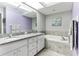 Bathroom featuring double sink, tiled floor, and large bathtub at 3815 Muirfield Ct, Palm Harbor, FL 34685