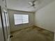 Minimalist bedroom with neutral carpet, ceiling fan, and natural light from window at 4506 Runabout Way, Bradenton, FL 34203