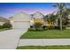 Charming single-story home with a well-manicured lawn, lush landscaping, and an attached two-car garage at 4623 Claremont Park Dr, Lakewood Ranch, FL 34211