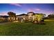 Elegant home exterior at twilight, featuring lush landscaping, palm trees, and a well-lit entrance at 4735 Trento Pl, Bradenton, FL 34211