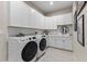 Well-organized laundry room featuring modern washer/dryer, white cabinets, and tiled backsplash at 4735 Trento Pl, Bradenton, FL 34211