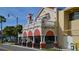 Unique building featuring restaurant with a second-floor balcony overlooking a wide sidewalk with chairs and potted plants at 503 Albee Farm Rd # B6, Venice, FL 34285