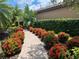 Beautiful walkway lined with vibrant red flowers, palm trees, and lush tropical plants at 5031 Serata Dr, Bradenton, FL 34211