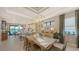 Elegant dining area featuring a long wooden table, modern light fixture, and views of the lake and kitchen at 5209 Barnett Cir, Lakewood Ranch, FL 34211