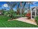 Landscaped backyard featuring lush greenery, a brick path, and an enclosed lanai at 5548 Simonton St, Bradenton, FL 34203