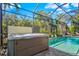 A hot tub is situated next to a sparkling swimming pool in a screened lanai with lush landscaping at 5670 Rock Dove Dr, Sarasota, FL 34241