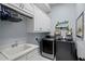 This laundry room is complete with washer, dryer, sink, storage, and decorative touches at 5670 Rock Dove Dr, Sarasota, FL 34241