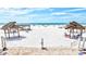 Expansive beach view featuring white sand, lounge chairs, and shaded cabanas under a bright, clear sky at 6140 Midnight Pass Rd # 103, Sarasota, FL 34242