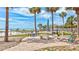 Outdoor space featuring a grill, table, lounge chairs, and palm trees with views of the ocean at 6140 Midnight Pass Rd # 103, Sarasota, FL 34242
