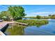 Dock and waterfront area with lush green vegetation, lounge chairs, and boat access at 6140 Midnight Pass Rd # 103, Sarasota, FL 34242