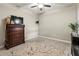Neutral bedroom features a dresser with a TV, ceiling fan, and large rug at 6280 Cassia St, Bradenton, FL 34203