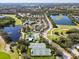 Aerial view of a golf course, community pool, tennis courts and parking lot surrounded by lush greenery and bodies of water at 7157 Strand Cir # 24-102, Bradenton, FL 34203