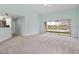 Open living room with sliding glass doors, carpet flooring, and a view of the pond at 7157 Strand Cir # 24-102, Bradenton, FL 34203