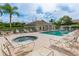 Community pool area with lounge chairs, hot tub, and building on a bright day with landscaping and palm trees at 7157 Strand Cir # 24-102, Bradenton, FL 34203
