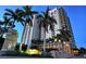 Exterior shot of the high-rise condominium with lush landscaping and decorative entry sign at dusk at 800 N Tamiami Trl # 312, Sarasota, FL 34236