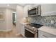 Contemporary kitchen with stainless steel appliances, elegant backsplash, and modern white cabinetry at 800 N Tamiami Trl # 312, Sarasota, FL 34236