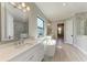 Modern bathroom featuring dual sinks, a soaking tub, and a large mirror at 8046 Anthirium Loop, Sarasota, FL 34240