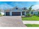 Charming single-story home with a three-car garage, manicured lawn, and a brick paved driveway at 8046 Anthirium Loop, Sarasota, FL 34240