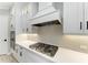 Close up of kitchen with stainless steel gas range, white countertops, cabinets, and modern range hood at 8046 Anthirium Loop, Sarasota, FL 34240