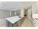 Open kitchen with a large gray island, white countertops, stainless steel appliances, and adjacent living area at 8046 Anthirium Loop, Sarasota, FL 34240