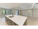 Kitchen island featuring a dual sink, quartz countertop, gray cabinetry, and an open view to the living area at 8046 Anthirium Loop, Sarasota, FL 34240