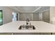 Kitchen island featuring a dual sink, quartz countertop, gray cabinetry, and view of the backyard pool area at 8046 Anthirium Loop, Sarasota, FL 34240