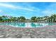 An inviting community pool surrounded by lush landscaping and lounge chairs under a clear blue sky at 8046 Anthirium Loop, Sarasota, FL 34240
