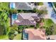 Top-down aerial view of a home with a screened-in pool, surrounded by lush landscaping and a pond at 8330 Abingdon Ct, University Park, FL 34201