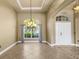 Bright living room featuring a decorative chandelier, large window, and neutral tile flooring at 8420 Sailing Loop, Lakewood Ranch, FL 34202