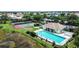 Aerial view of pool, tennis courts, and clubhouse surrounded by lush greenery, landscaping, and neighborhood at 854 Dahoon Cir, Venice, FL 34293