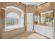 Elegant bathroom with a large soaking tub under a frosted glass block window and double sink vanity at 854 Dahoon Cir, Venice, FL 34293