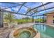 Screened-in pool and spa with a surrounding paver patio, and lush landscaping at 854 Dahoon Cir, Venice, FL 34293