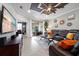 Comfortable living room features a dark leather sofa, modern ceiling fan, and sliding glass door to screened lanai at 12151 Amica Loop, Venice, FL 34293