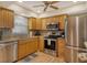 Well-lit kitchen features stainless steel appliances, wood cabinets, and granite countertops at 1783 Lake Pl # 1783C, Venice, FL 34293