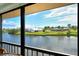 Scenic water view from screened lanai showcasing waterfront homes under a blue, partly cloudy sky at 1783 Lake Pl # 1783C, Venice, FL 34293