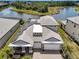 Stunning aerial view of a modern home with solar panels, a gray tile roof, and a serene lake backdrop at 19912 Bridgetown Loop, Venice, FL 34293