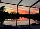 Picturesque sunset view over a tranquil lake from the screened-in pool area, offering a serene atmosphere at 19912 Bridgetown Loop, Venice, FL 34293