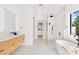 Modern bathroom with wood vanity, walk-in shower, soaking tub and view into the walk-in closet at 2177 Sunnyside Pl, Sarasota, FL 34239