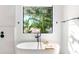 Modern bathroom featuring a soaking tub with a stylish faucet and a serene view from the window at 2177 Sunnyside Pl, Sarasota, FL 34239