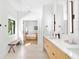Bright bathroom featuring double sinks, modern fixtures, and an adjacent bedroom visible in the mirror at 2177 Sunnyside Pl, Sarasota, FL 34239