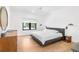Bright, minimalist bedroom with hardwood floors, modern lighting, and a large window at 2177 Sunnyside Pl, Sarasota, FL 34239