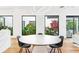 Dining room featuring a round table, modern chairs, hardwood floors, and windows overlooking lush greenery at 2177 Sunnyside Pl, Sarasota, FL 34239