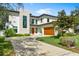 Modern house featuring a manicured lawn, stone accents, an orange door and attached garage at 2177 Sunnyside Pl, Sarasota, FL 34239