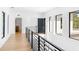 Bright hallway with wooden floors, metal railing, and modern black framed windows bringing in natural light at 2177 Sunnyside Pl, Sarasota, FL 34239