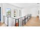 Modern hallway featuring a black metal railing, light hardwood floors, and plenty of natural light at 2177 Sunnyside Pl, Sarasota, FL 34239
