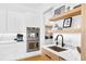 Modern kitchen with stainless steel appliances, white cabinetry, marble countertops, and wood shelving at 2177 Sunnyside Pl, Sarasota, FL 34239